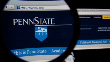 Penn State homepage on a monitor screen through a magnifying glass 