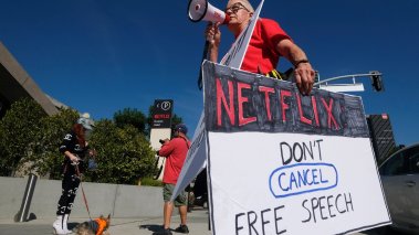 Supporter of comedy and free speech holds signs while people rally in support of the Netflix transgender walkout in Los Angeles 