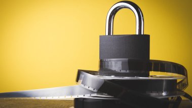 Film reel and padlock on a yellow background