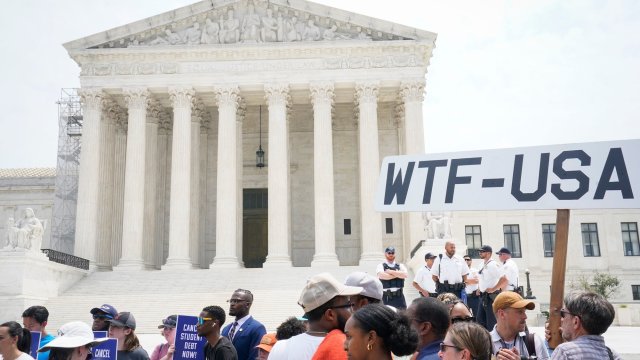 Protesters in front of the Supreme Court holding a sign that reads "WTF-USA"
