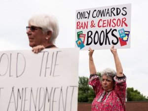 Opponents to a proposed library policy in Central Bucks School District holding up signs comparing the policy to censorship and book banning