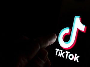 Finger touching a screen display with the TikTok symbol