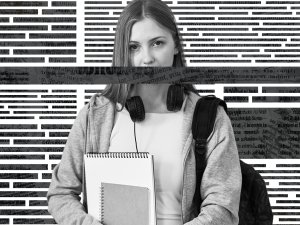 Student holding notebooks standing in front of newspaper background. A stripe of text covers her mouth.