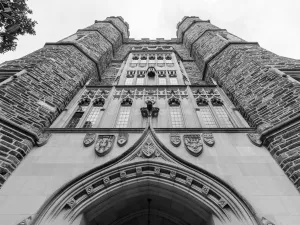 Black and white photograph of Duke University stone campus building with the perspective looking up to the sky, so the building appears imposing.