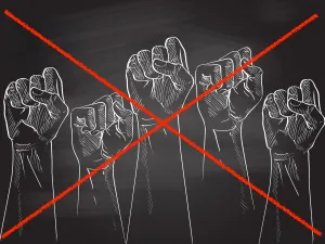 Protest fists drawn on black chalkboard with a red strike crossing them out.