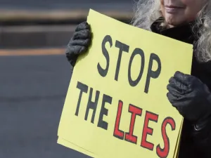 Rockville, MD -  January 11, 2026: Protester holding a sign at the Ice Out for Good protest that says "STOP THE LIES".