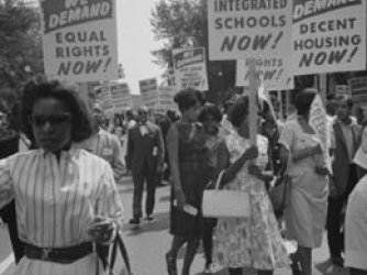 A black and white image of Black people protesting in the streets with signs that say We March for Integrated Schools Now! 