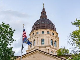 Dome of the Kansas State Capital Building in Topeka with the state flag in the foreground