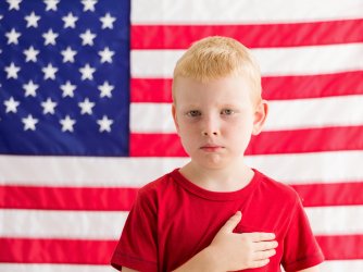 Boy in front of American flag with hand over heart