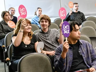 Students holding up "Let's Talk" fans at an event in Utah