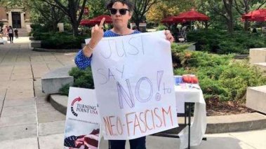 Image of Courtney Lawton holding a sign that reads, “Just say No! to Neo-Fascism."