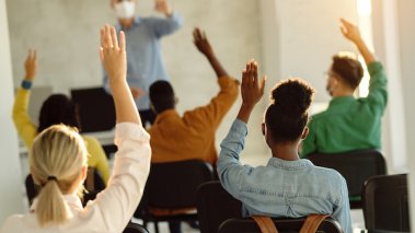 Students raising hands in a classroom - CREDIT Drazen Zigic Shutterstock