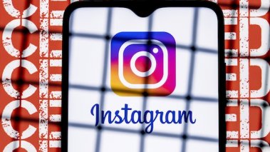 Instagram social network logo on the smartphone screen behind the bars on the background with the inscription censored.