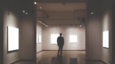 Person browsing art gallery with blank paintings