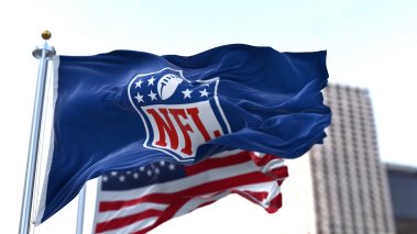 NFL flag waving with a blurred city building in the background