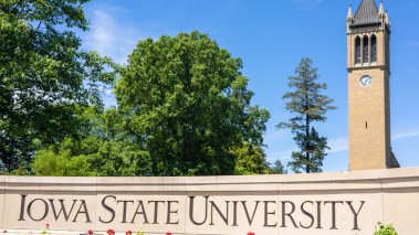 Iowa State University sign and campanile with green environment and blue sky 