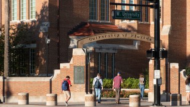 Students walk through the entrance sign at University of Florida 