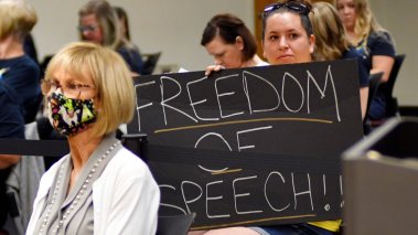 Woman holds a sign reading "freedom of speech" during a Brevard County School Board meeting 