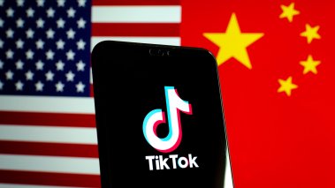 TikTok app logo on a smartphone screen and flags of China and United States 