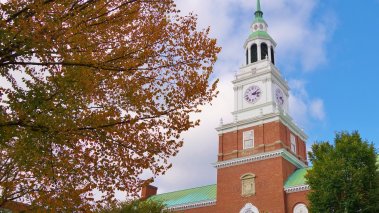 With a tree in fall colors filling most of the left half of the frame this is a nice view of the library bell tower and blue sky on the campus of Dartmouth College in Hanover, New Hampshire.