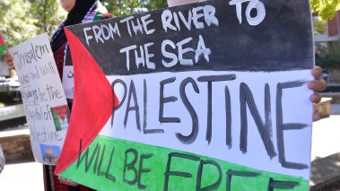 Protestor holding a sign that reads "From the River to the Sea, Palestine will be free"
