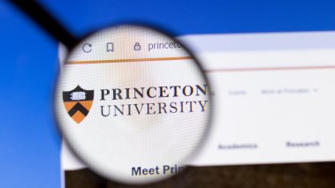 Princeton University website homepage logo visible on display screen under a magnifying glass