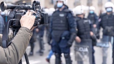 A cameraman films riot police at a protest