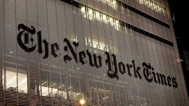 New York Times headquarters at night with lights shining through the facade