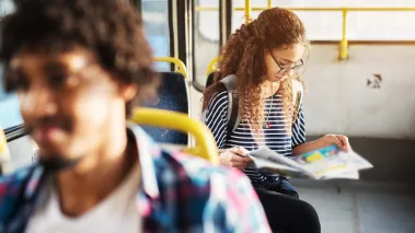 student reading newspaper on bus