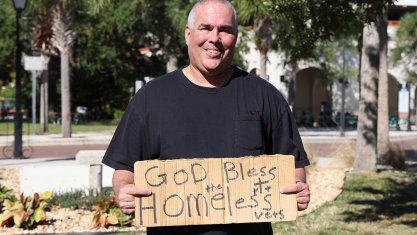 FIRE plaintiff Jeff Gray holds a sign reading "God bless homeless vets"