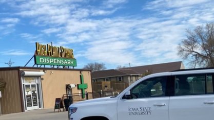 Iowa State University car in front of dispensary.