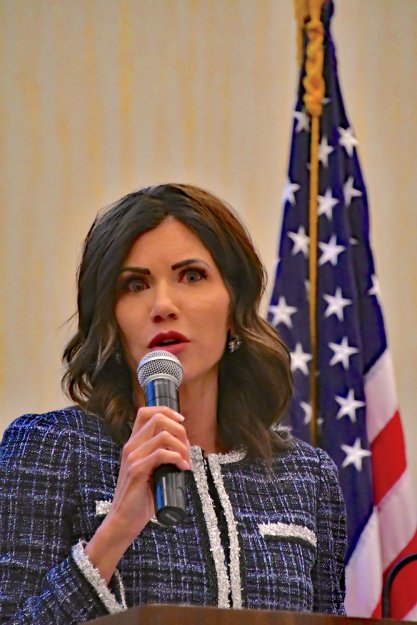 South Dakota Gov Kristi Noem speaking at an event in front of an American flag