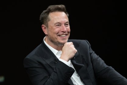 Elon Musk sitting in a chair against a black background