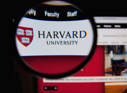 Photo of Harvard University homepage on a monitor screen through a magnifying glass 