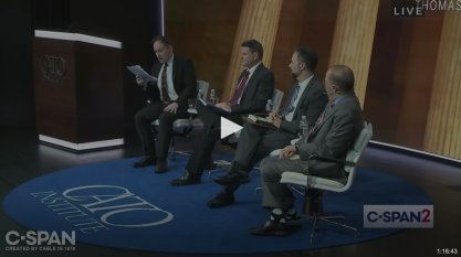 Four men dressed in suits on a stage at the Cato Institute 