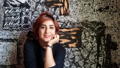 Atena Farghadani sitting for a photograph in front of a painting.