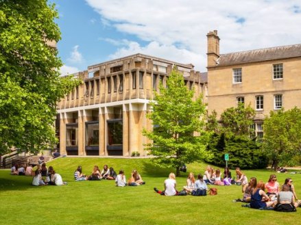 Students sitting together on grass near a college building