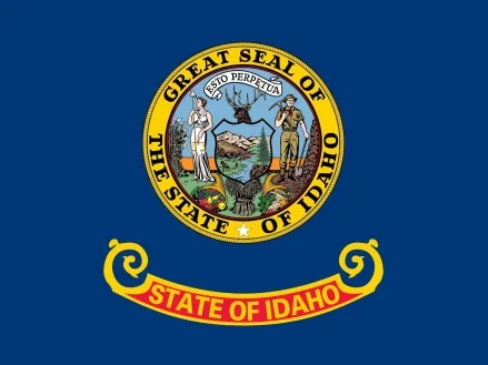 A state seal above the words "State of Idaho" in gold letters on a red and gold band on a blue field. The seal depicts a miner and a woman representing equality, liberty and justice. 