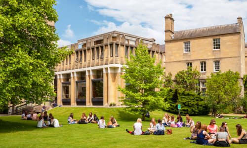 students sitting on the grass on campus