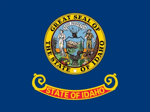 A state seal above the words "State of Idaho" in gold letters on a red and gold band on a blue field. The seal depicts a miner and a woman representing equality, liberty and justice. 