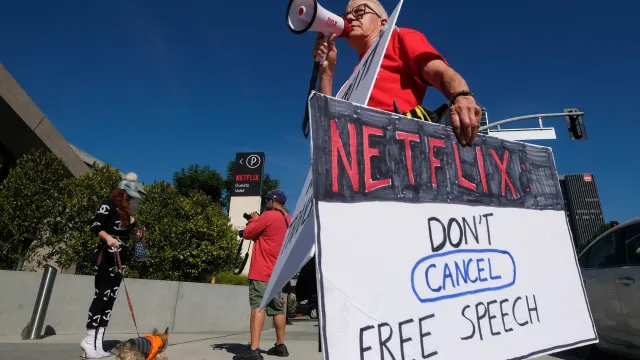 Supporter of comedy and free speech holds signs while people rally in support of the Netflix transgender walkout in Los Angeles 