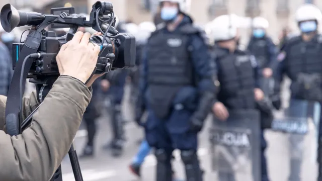 A cameraman films riot police at a protest