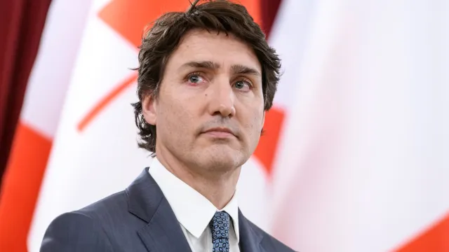 Canadian Prime Minister Justin Trudeau standing before a row of Canadian flags