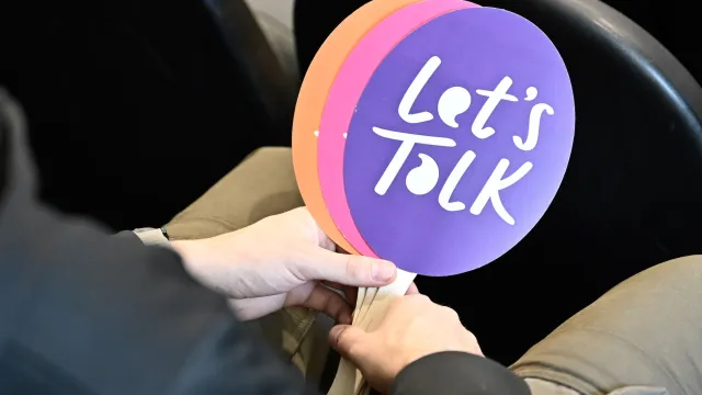 Student holding "Let's Talk" fans at an event in Utah